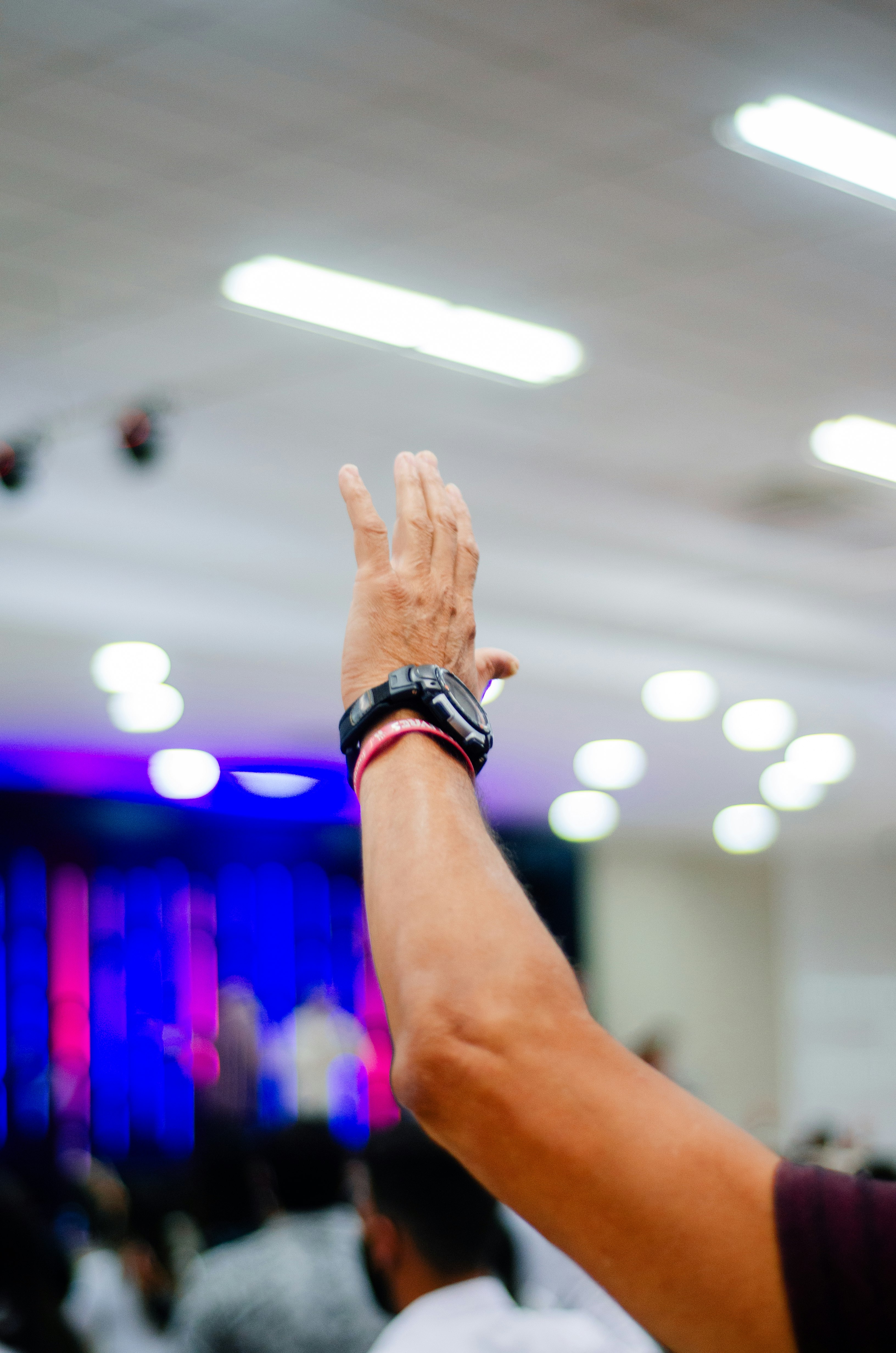 person wearing black watch raising his hand